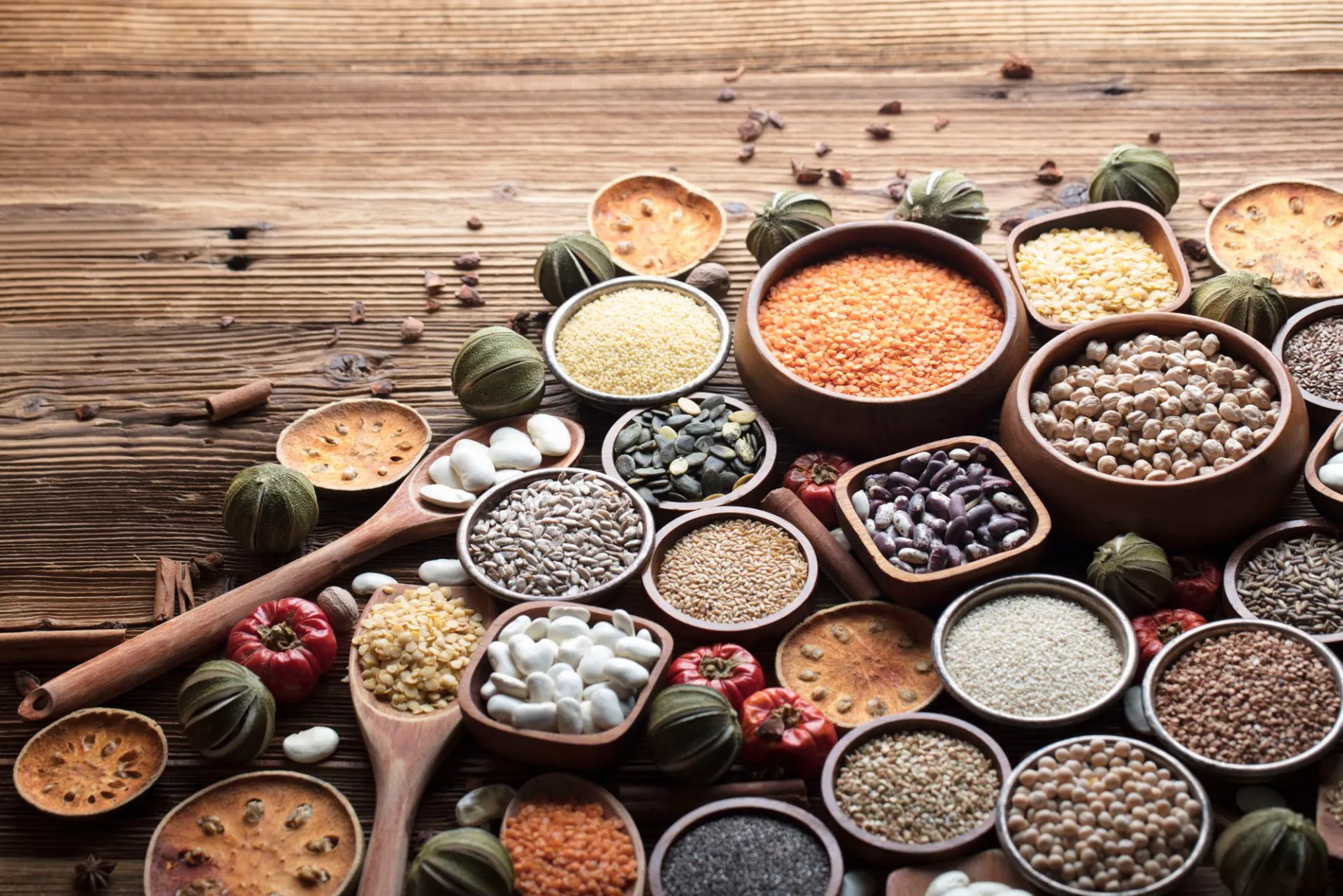 Rice, lentils, chickpeas and whole spices in wooden bowls on a rustic table.
